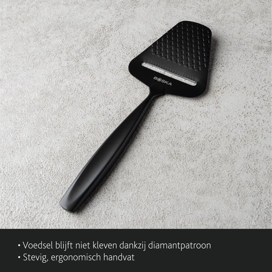 Zwarte kaasschaaf op een grijze ondergrond. Voedsel kleeft niet door diamandpatroon. Stevig, ergonomisch handvat.