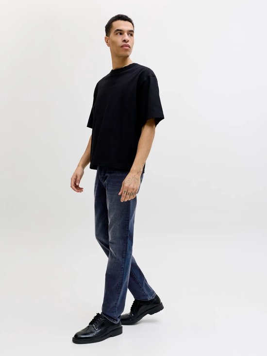 Man met een zwarte oversized t-shirt en blauwe jeans, loop van opzij.