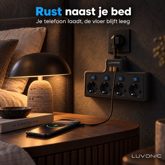 Zwarte Luvonic stekkerdoos bij een bed, met een telefoon die oplaadt via USB.