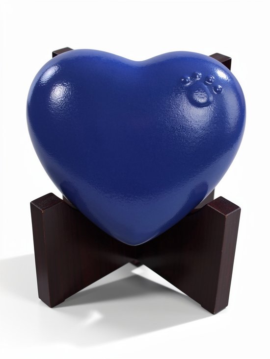 Blauwe, hartvormige urn met pootafdruk op een donkere houten standaard tegen een witte achtergrond.