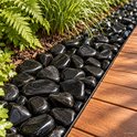 Gepolijste, glanzende, zwarte rivierkiezels liggen naast houten planken en groene planten.