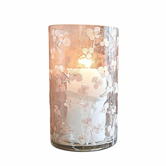 Cilindrisch glazen windlicht met roze bloemmotieven en een brandende witte kaars binnenin.