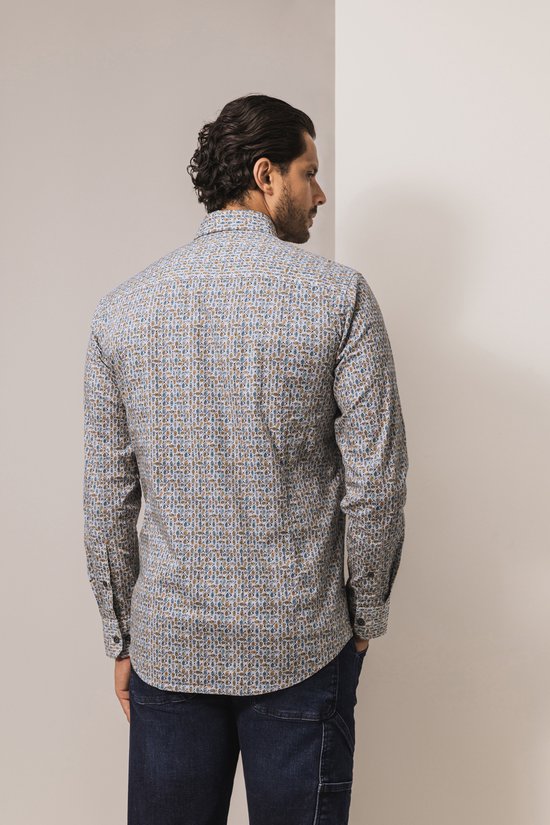 Achteraanzicht van een model dat een State of Art overhemd met een blauw en geel bladmotief en donkere jeans draagt.