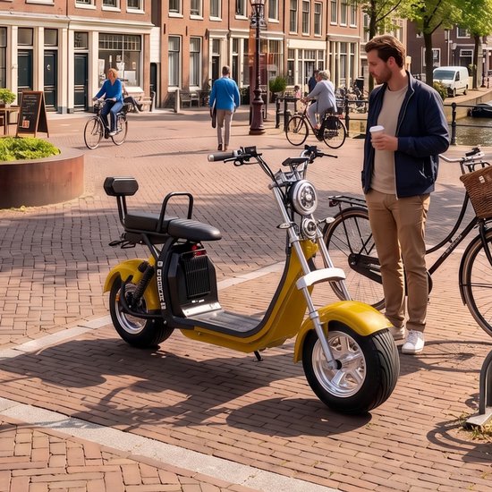 Gele Ecowielen elektrische scooter met retro design, een man staat ernaast met een kop koffie.