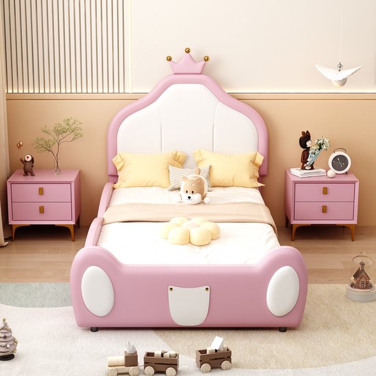 Roze kinderbed met wit hoofdbord, kroonaccent en witte 'koplampen'.