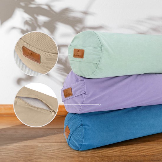 Drie gestapelde yogabolsters in pastelgroen, paars en blauw, met ronde details en een bruin leren label.