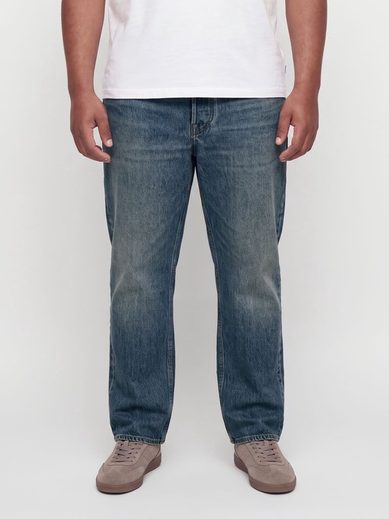 Gedetailleerde opname van de voorkant van blauwe relaxed fit jeans, met knopen en zakken.