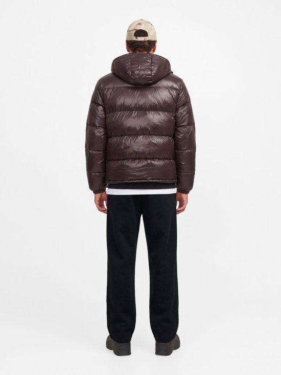 Rug van model in donkerbruine gewatteerde jas met capuchon en een zwarte joggingbroek.