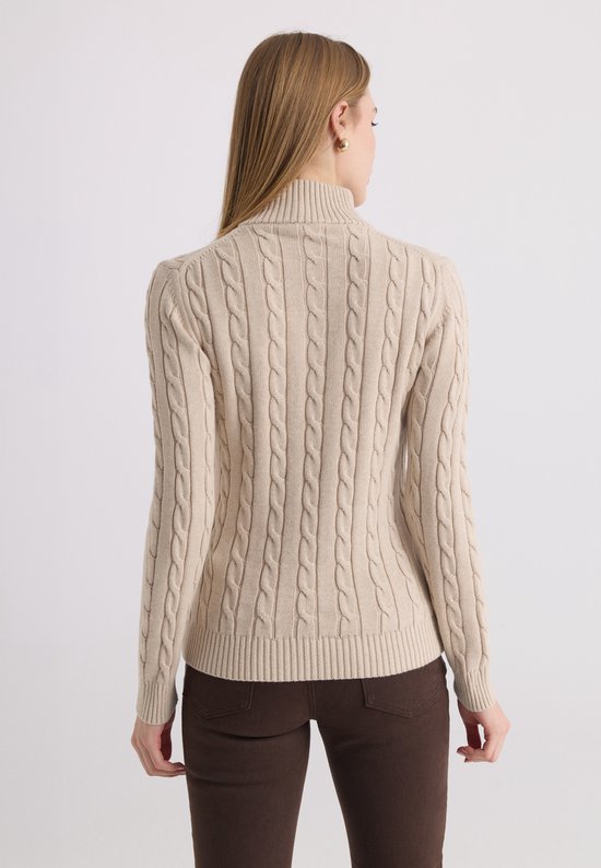 Achterkant van een beige kabelgebreide trui met ritskraag, gedragen door een model.
