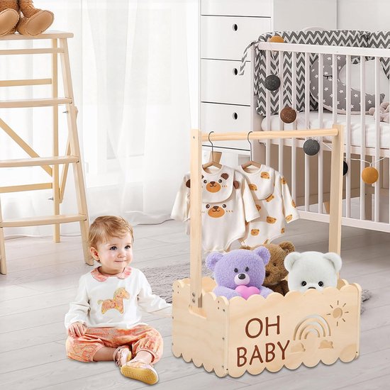 Baby bij houten kledingrek met babykleding en knuffels. Krat met 'OH BABY' en regenboog versiering.