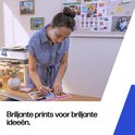Vrouw in blauwe jurk schrijft op een print aan een bureau. Tekst: Briljante prints voor briljante ideeën.