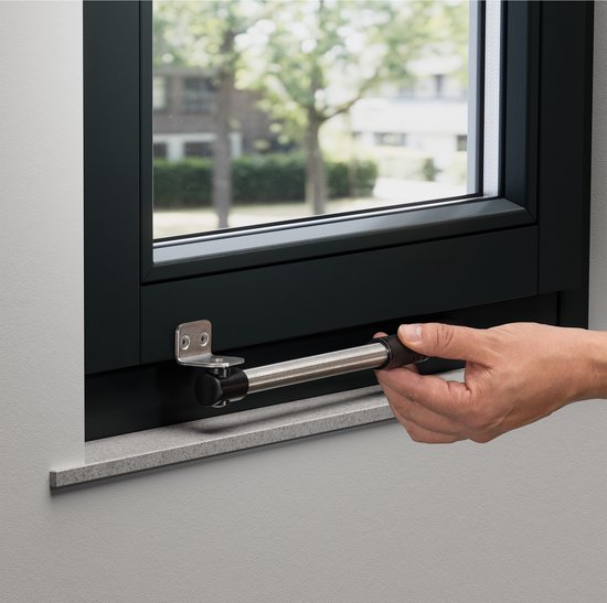 Hand bedient een zwart-metalen raamuitzetter gemonteerd op een donker raamkozijn.