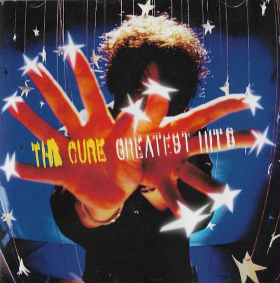 The Cure Greatest Hits albumhoes: een hand voor het gezicht op een blauwe achtergrond met fonkelende sterren.