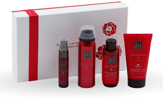 Vier Rituals Ayurveda producten in rode verpakking geplaatst voor een witte geschenkdoos met rode linten.