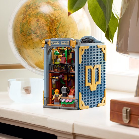 Gesloten LEGO Boekhandel, blauw met gouden details, staand naast een globe.
