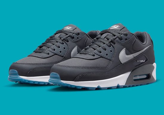 Een paar donkergrijze Nike Air Max 90 sneakers met witte en lichtblauwe zolen.