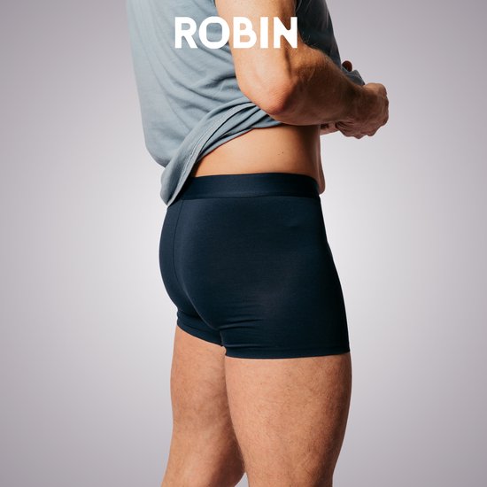 Zijaanzicht van een man in donkerblauwe Robin boxershorts. De shorts hebben een gladde, donkere stof.