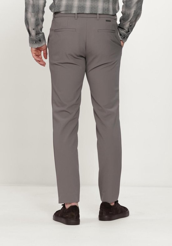 Zicht op de achterkant van een grijze chino broek gedragen door een man met een grijze geruite blouse en bruine sneakers.