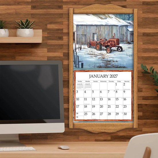 Een kalenderpagina voor januari 2027 met een schilderij van een tractor in de sneeuw voor een houten schuur, opgehangen aan een houten kalenderframe aan een muur.