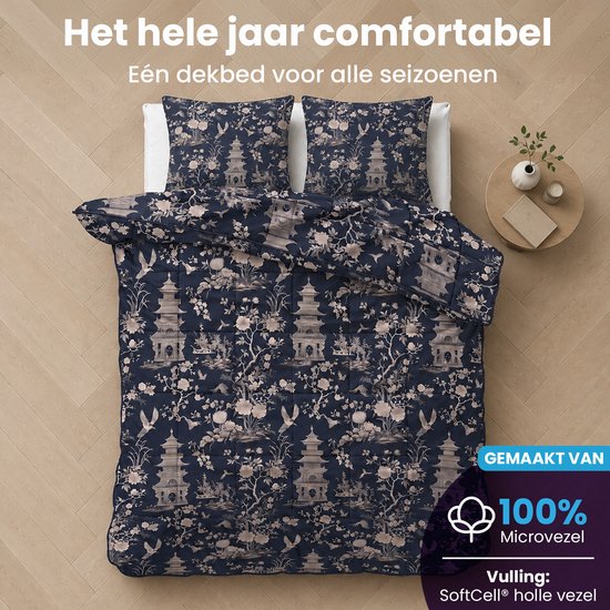 Opgemaakt bed met een blauw dekbed en kussens met pagode-, bloemen- en vogelprint.