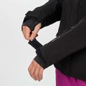 Vrouw verstelt de klittenbandsluiting van de mouw van haar zwarte ski-jas.