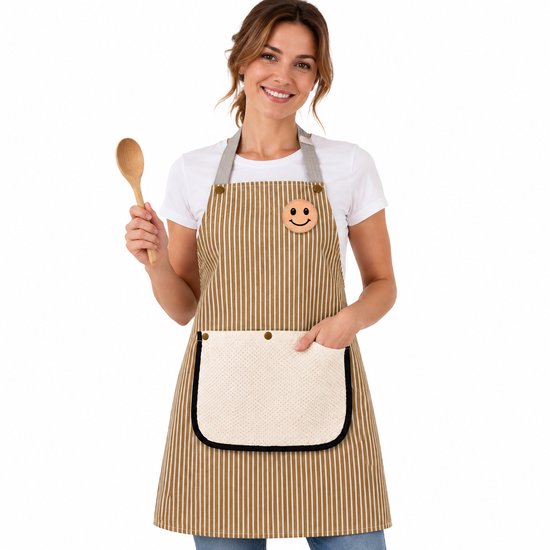 Femme portant un tablier à rayures brun-blanc avec un patch smiley, tenant une cuillère en bois. La poche est crème avec un motif tissé beige.