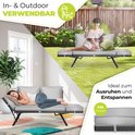 Een vrouw rustend op een grijze tuinbank in een tuin, een andere vrouw slaapt erop.