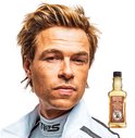 Man met warrig blond haar in racekleding naast een fles Reuzel Grooming Tonic.