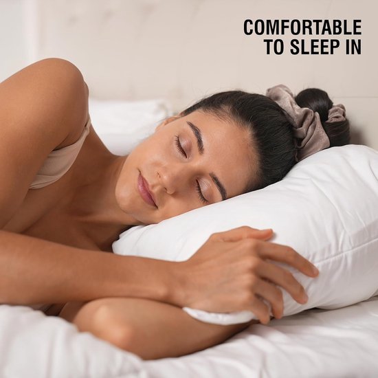 Vrouw met een bruin haarelastiekje in haar haar slaapt comfortabel op een kussen. Tekst: COMFORTABLE TO SLEEP IN.