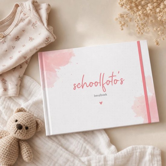 Wit invulboek met roze aquarelaccenten, naast een knuffelbeer en babykleertjes op een zachte achtergrond.