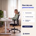 Vrouw werkt aan een wit Stane zit-sta bureau. Met informatie over obstakelstop, verstelbare voeten en kabeldoorvoer.