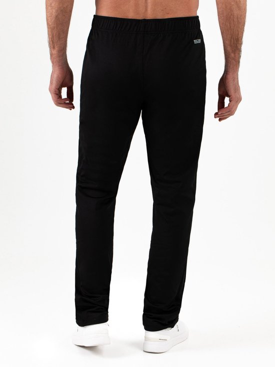 Man van achteren in een zwarte trainingsbroek van Sjeng Sports met merklabel in de nek.