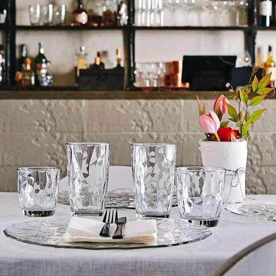 Une table dressée avec des verres de différentes tailles, des serviettes et des couverts.