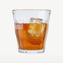 Een doorzichtig Duralex Picardie glas gevuld met oranjebruine drank, ijs en sinaasappelschil.