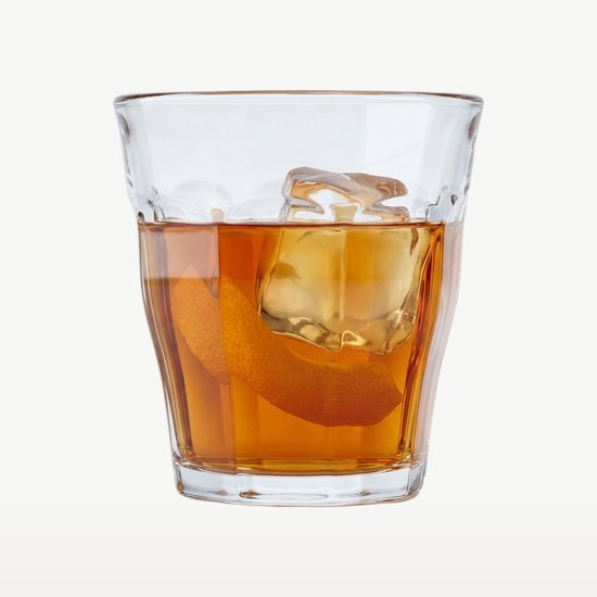 Een doorzichtig Duralex Picardie glas gevuld met oranjebruine drank, ijs en sinaasappelschil.