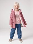 Meisje met blond haar, lachend, draagt een roze regenjas met teddy voering, roze trui met hartjesprint en spijkerbroek.
