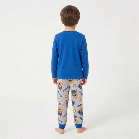 Jongetje van achteren gezien in een blauwe pyjama, met Chase van Paw Patrol-patroon op de broek.