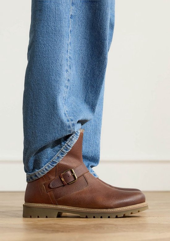 Botte en cuir cognac avec boucle, portée avec un jean.
