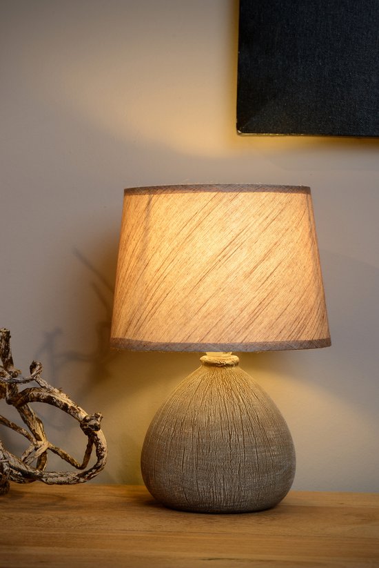 Lampe de table marron texturée avec abat-jour conique, à côté d'une branche décorative.