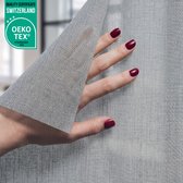 Hand met rode nagellak raakt grijze, geweven raamfolie aan. Kwaliteitscertificaat OEKO-TEX.