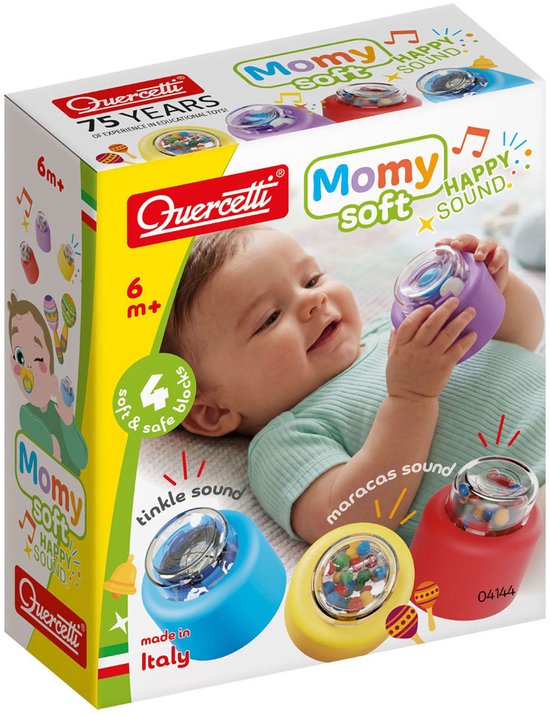 Doos met baby speelgoed van Quercetti. Toont een baby die met drie zachte blokken speelt: blauw, geel en rood. Met "Mommy soft HAPPY SOUND" tekst.