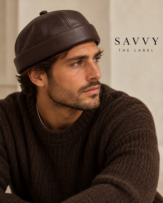 Man draagt bruine PU-leren docker muts en gebreide trui. Tekst: SAVVY THE LABEL.