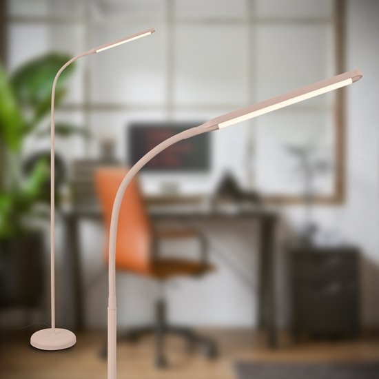 Een beige vloerlamp met een gebogen arm, deels in beeld, met een bureaustoel en bureau op de achtergrond.