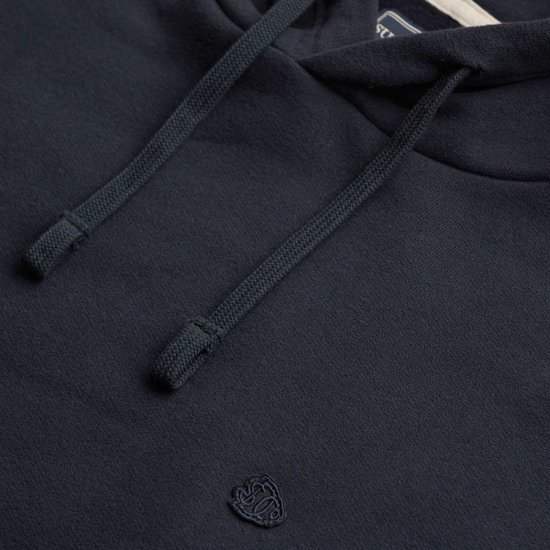 Close-up van de donkerblauwe hoodie met trekkoorden en het kleine geborduurde Superdry logo.