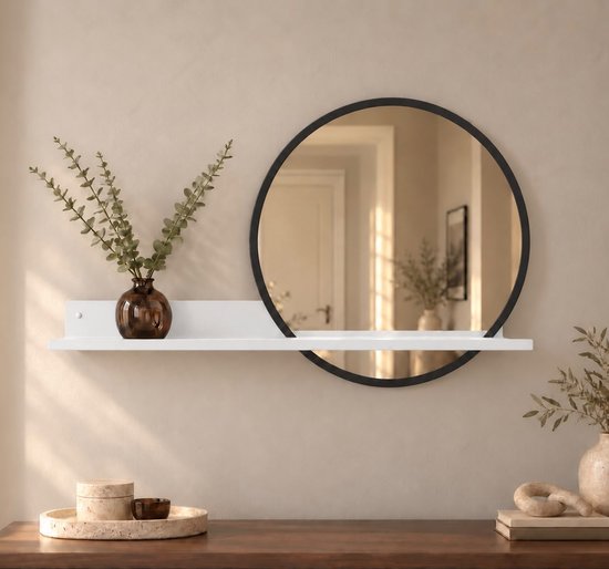 Witte wandplank met een ronde zwarte spiegel, gedecoreerd met een bruine glazen vaas met takjes op een beige muur.