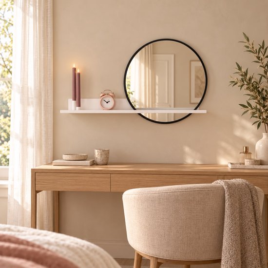 Witte wandplank met ronde zwarte spiegel, twee paarse kaarsen en roze klok in een modern, licht interieur.