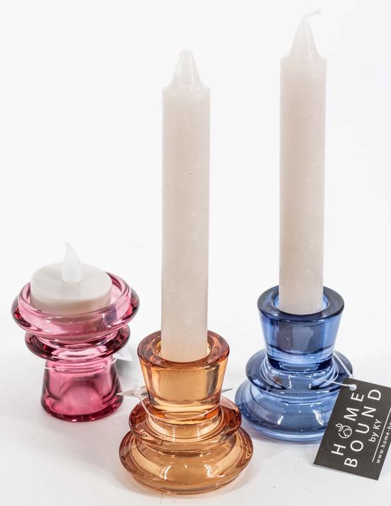 Drie glazen kandelaars in roze, amber en blauw met witte kaarsen.