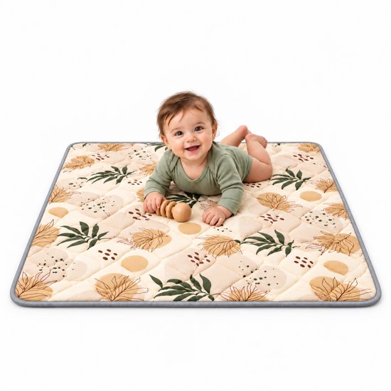 Baby ligt op een vierkant, gewatteerd speelkleed met botanisch patroon in beige- en groentinten.