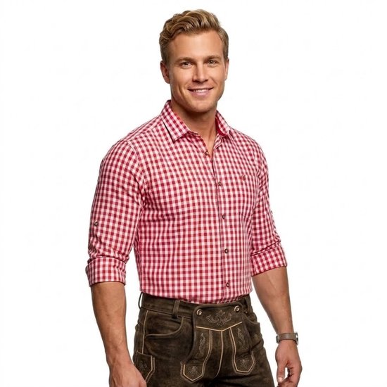 Man in een rood-wit geruit overhemd en een traditionele bruine lederhosen, glimlachend naar de camera.