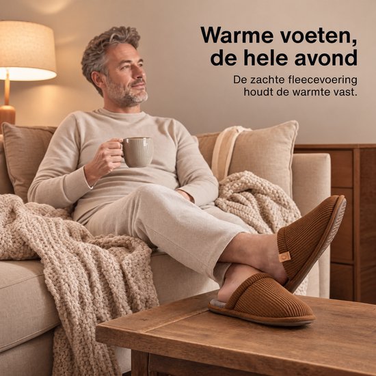 Man ontspant op de bank met warme bruine corduroy pantoffels en een mok in de hand.